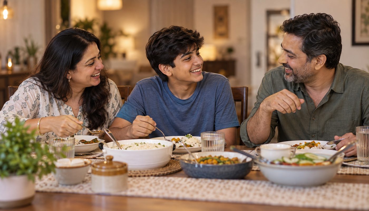 Indian family — mother, teenage son and father — laughing together over dinner